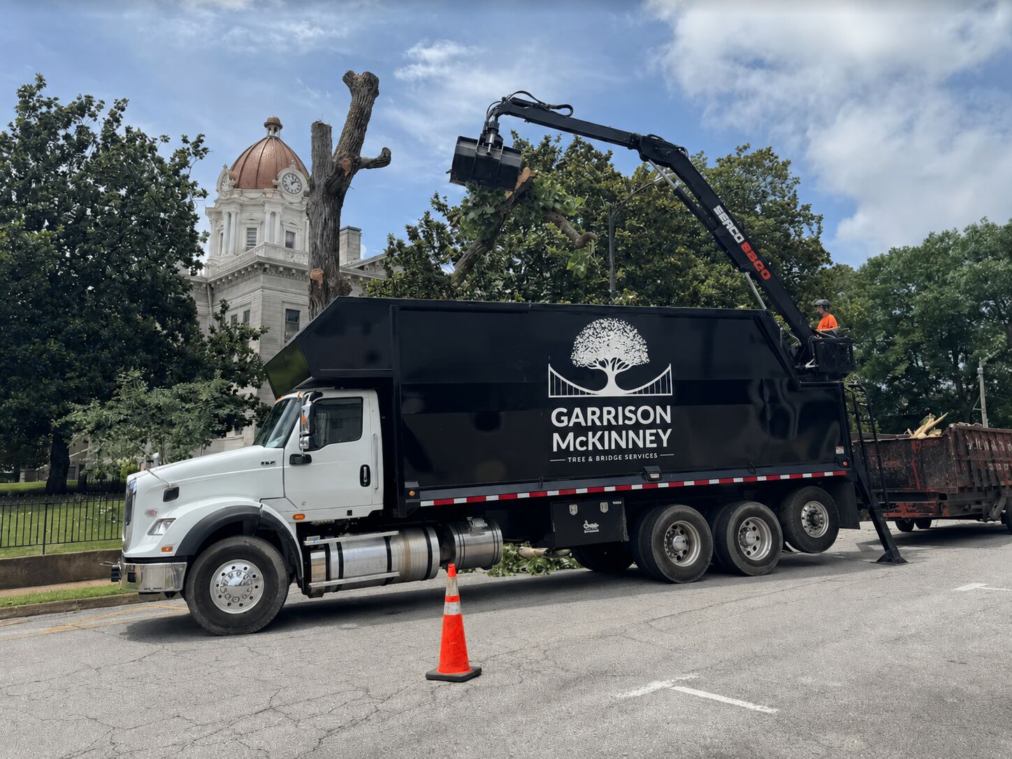Grapple truck trimming trees beside a courthouse